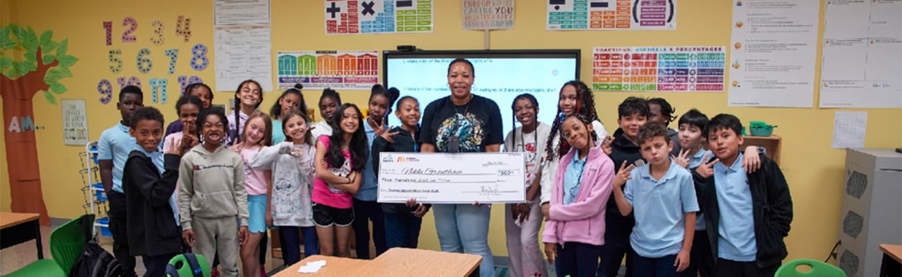 teacher with large check and group of students in classroom