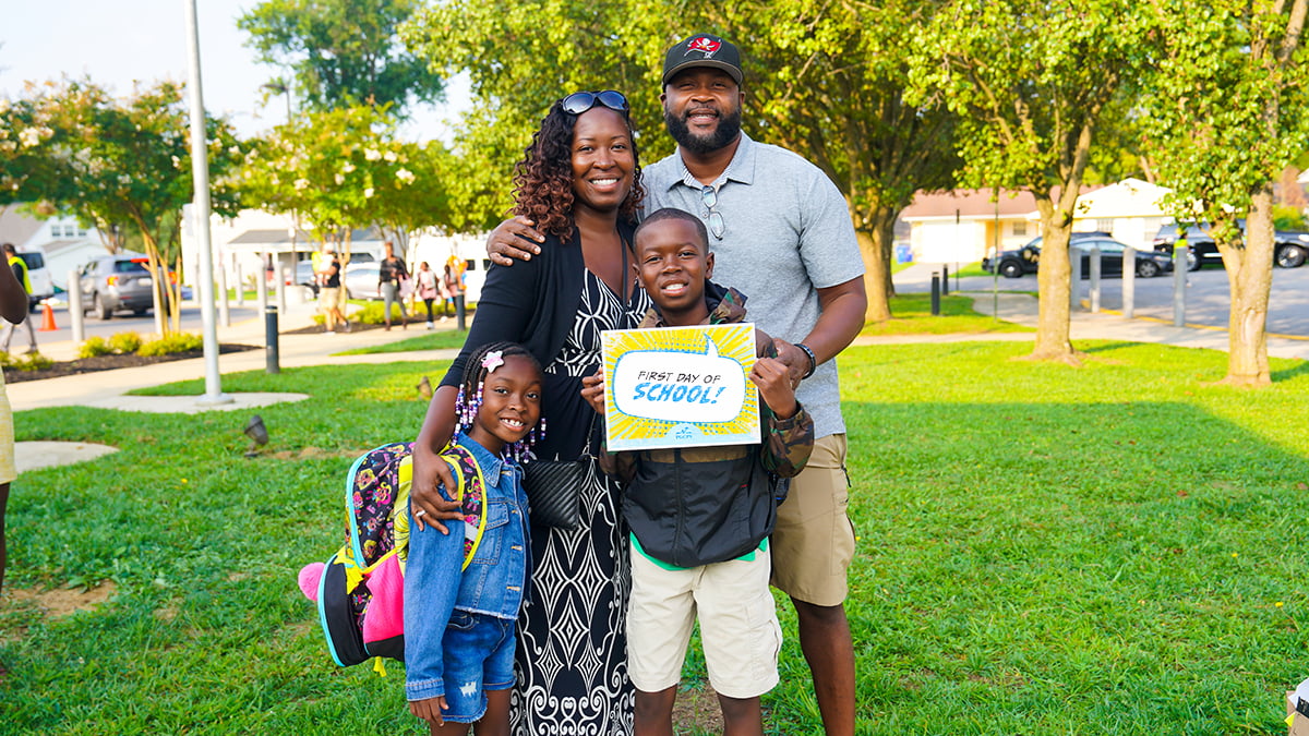 family-outside-with-first-day-of-school-sign