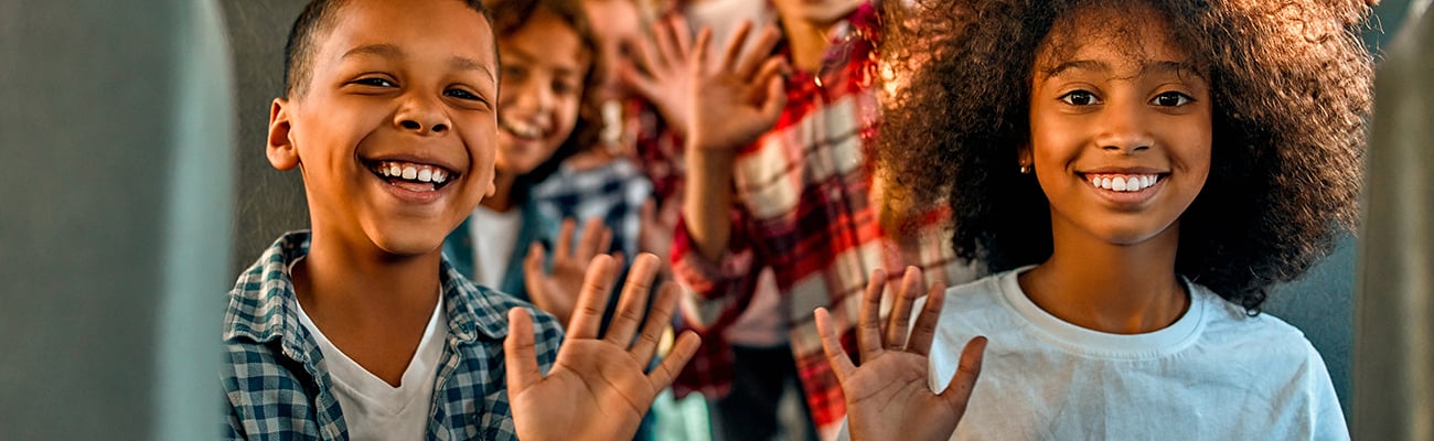 elementary-students-on-bus-holding-up-hands