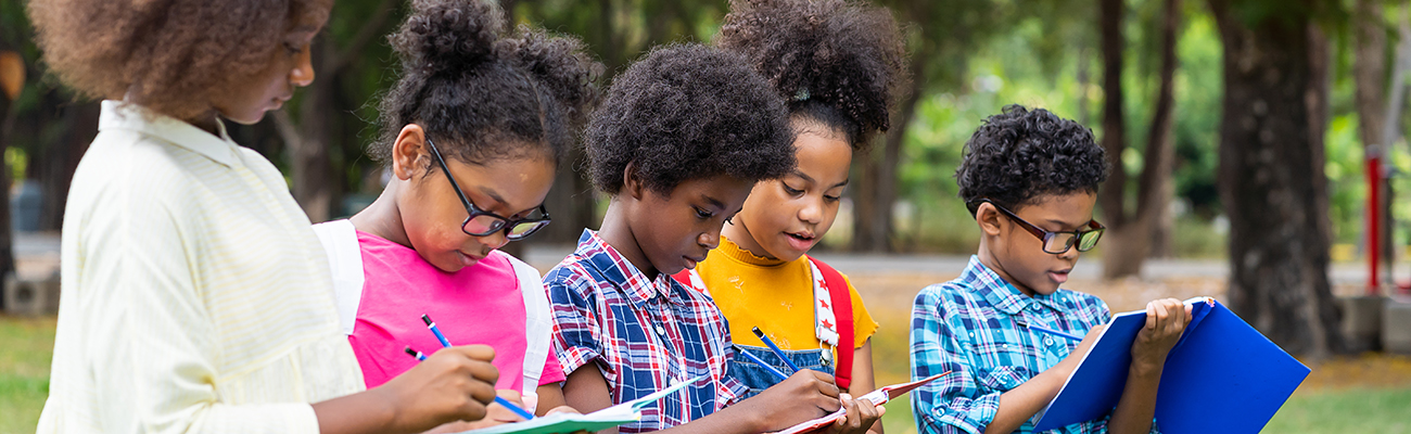 group-elementary-students-taking-notes-in-notebooks-outdoors