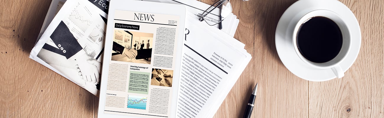 news-tablet-on-folded-newspaper-cup-of-coffee-glasses-and-pen