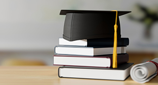 books on table with graduation cap and diploma